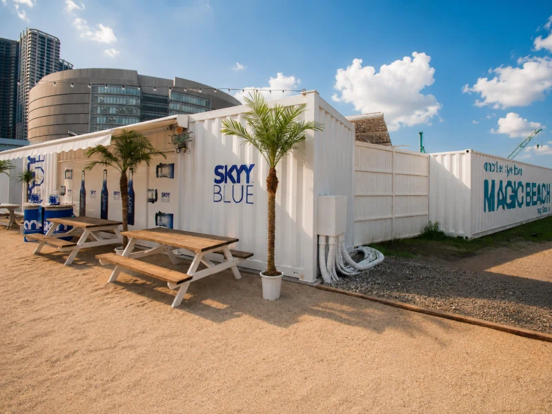 東京・豊洲のTOKYO MAGIC BEACH COMMERCIAL STREETに設置された仮設コンテナ建築のBBQスペース。Yustellar Cuboxが手掛けた16ユニット構成のモジュール建築で、イベント施設・モバイル店舗・期間限定商業空間に対応したB2B向け施工事例です